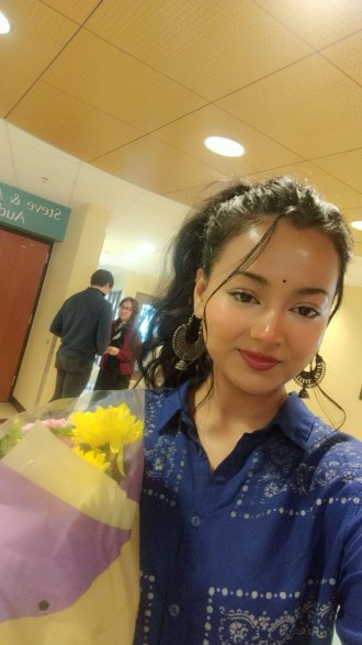 An international student poses with flowers at Miller Auditorium.