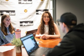 Jadazay Ledbetter sits at a table with other students during a business meeting.
