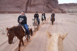 Students ride horses through a canyon in the Desert Southwest.