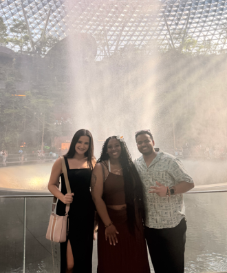 Three WMU study abroad students stand in front of a large fountain at the Singapore airport.
