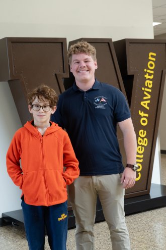 Vail Fear and Evan Simpson stand in front of the College of Aviation W.