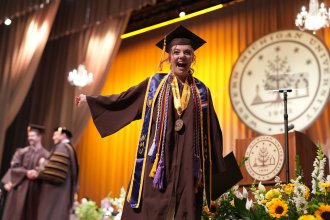 Honors grad Molly Cochran grins as she walks across the stage at commencement.