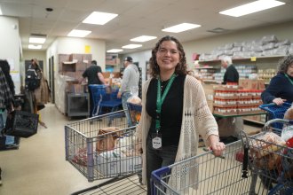 Grace Mulock stands in a food pantry with two grocery carts.
