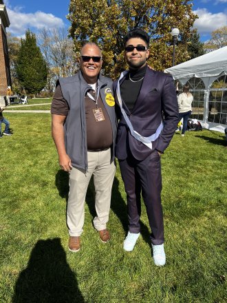 An international student stands with the former University president at a Homecoming celebration.