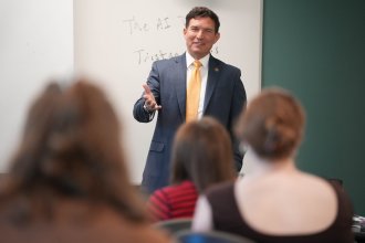President Russ Kavalhuna talks at the front of a classroom.