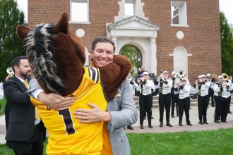 President Russ Kavahuna hugs Buster Bronco at Homecoming.