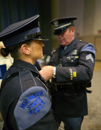MSP Trooper Rachel Moore is pinned by her father during her recruit school graduation ceremony.