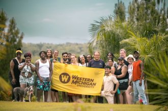 A group of WMU students holds a WMU flag in Dominican Republic.