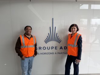 Raymond Miller wears an orange work vest on an airplane industry tour.