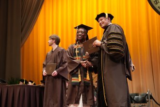 Shaniya Tate receives her diploma on stage from WMU President Russ Kavalhuna.