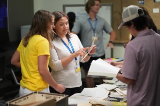 Cold Case Program students look at evidence on a table.