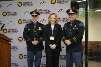 Shelby Wilmot stands on a stage between two MSP troopers.
