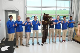 Buster Bronco stands with flight students.