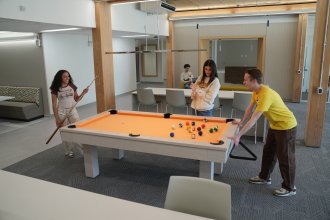 Students play pool in a community space inside Valley Oaks.