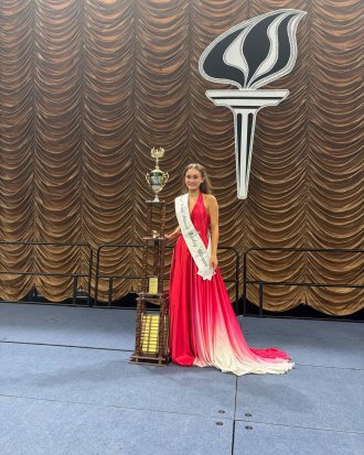 Emily Brown wearing an evening gown standing next to her Twirling trophy.