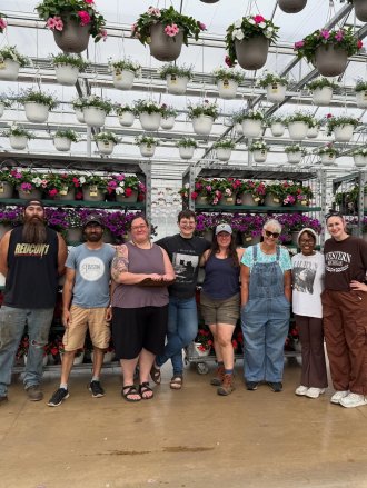 A group of people stands in a greenhouse.