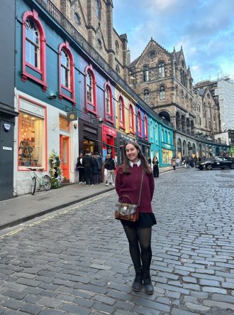WMU study abroad student, Emma Simpson, stands in the street in Scotland in front of old architecture. 