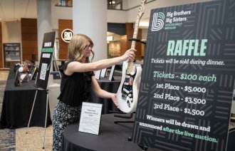 Mackenzie Flood puts a guitar on a stand.