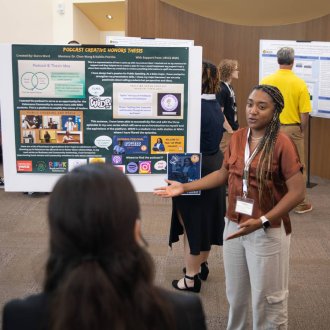 An honors student presents her research poster in the honors college lounge. 