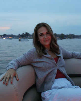 Halle Woodard sits in a boat just after sunset, smiling.