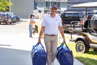 President Russ Kavalhuna carries bags into a residence hall.