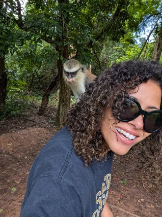 WMU study abroad student in a Ghana forest with a monkey on her back. 