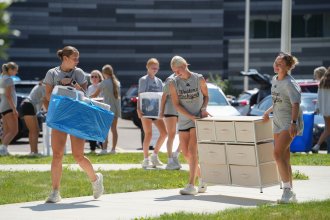 Students carry items into a residence hall.