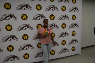 A student waves an American flag and the flag of her home country at WMU's International Student Orientation.