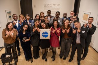 Members of Western's Fulbright community pose in a group and make "W" hands to celebrate Western. They hold a Fulbright sign at a University event.