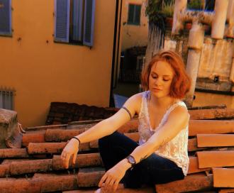 Melina Wilcox sitting on roof abroad.