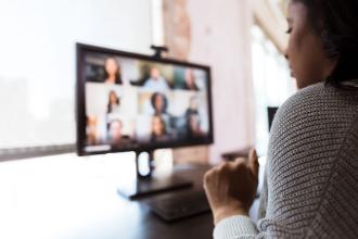 A lady on a computer listening to a virtual meeting