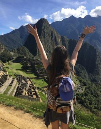 A female student back portrait, facing Machu picchu historical site in Peru.