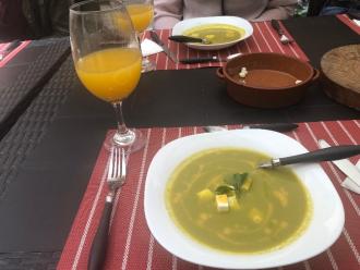 A bowl of soup with a glass of orange juice in a restaurant
