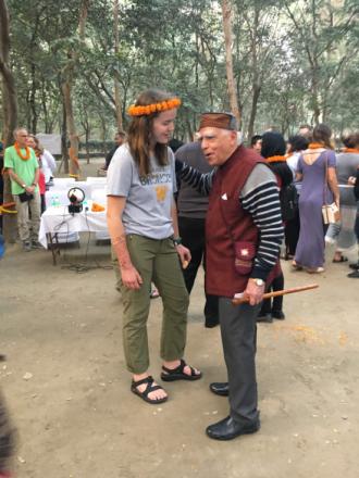 A female WMU student talking with an old Indian man in a festival.