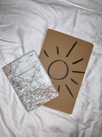 An American passport and a notebook on a bed.