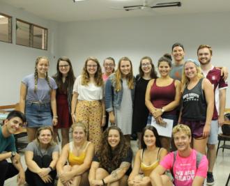 A group of smiley male and female students in a classroom.