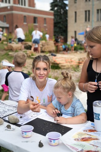 Mary Howe kneels down at a table to show a child owl pellets.