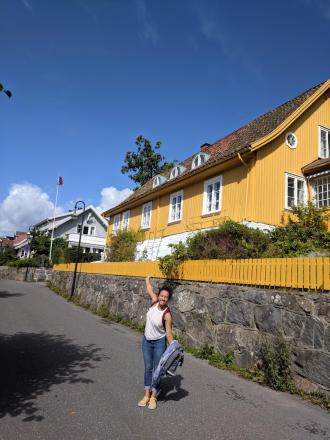 Catherine in front of a picuresque yellow house in Norway