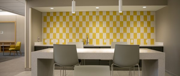A Valley Oaks kitchenette with sleek white furniture against a yellow and white tiled wall.