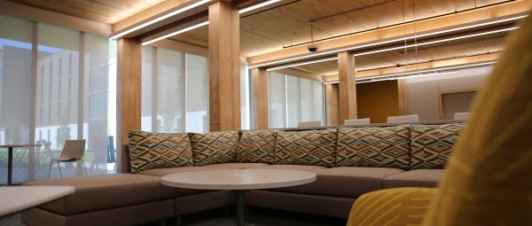 A warmly lit residence hall lounge with wood ceilings and colorful furniture.