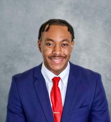 Headshot of Michael Harmon in blue suit and red tie on a grey background