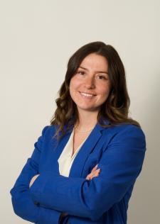 Headshot of Emily Styburski in a blue jacket and white blouse on an off-white background