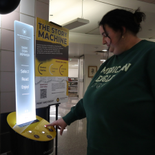 A student presses a button on the Story Machine in Waldo Library.