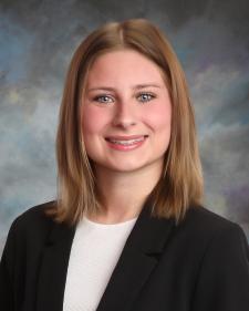 Headshot of Desiree Krawczyk in a white top and black blazer on a grey background
