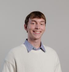 Headshot of George LaForce in a white sweater with a blue collar on a white background