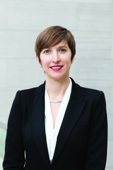 Woman wearing a white blouse and dark blazer with short brown hair, smiling.