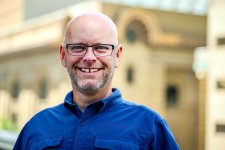 Professional photo of Kurt Wilson standing outdoors in a dark blue button down shirt