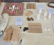 An assortmant of carved items such as boardgames and small figurines, all laid out on a table.