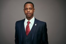 Headshot of Tre Harris in a suit with a red tie on a grey background
