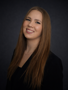 Headshot of Cheyenne Niemann in a black blazer on a black background